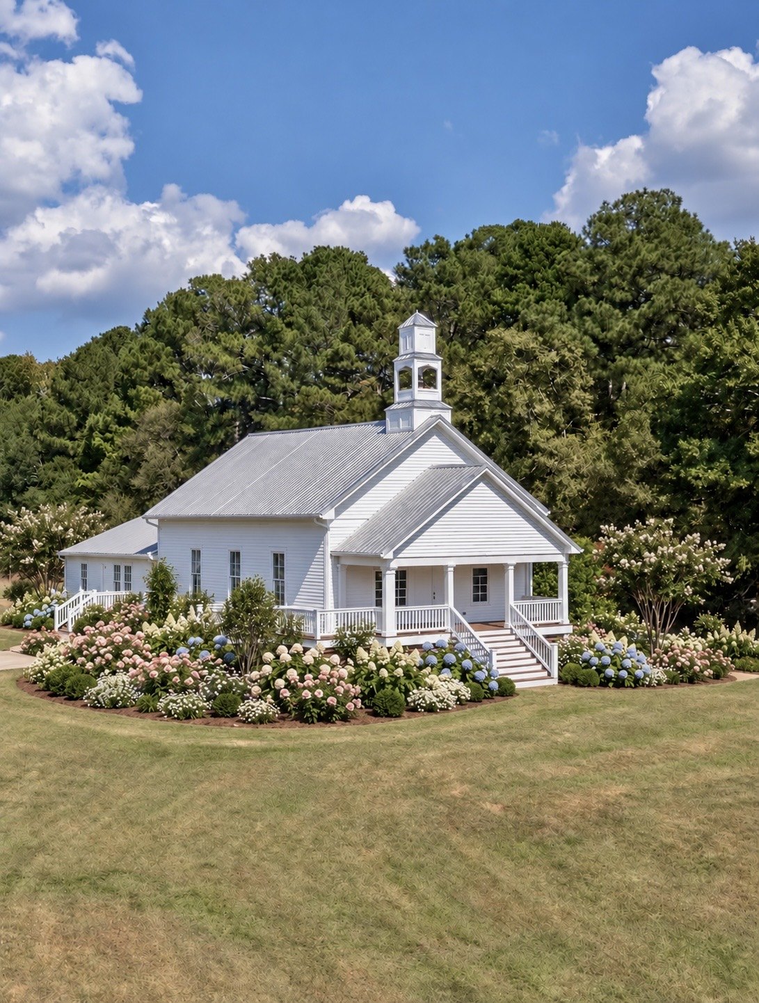 The white chapel with its steeple, ringed in hydrangeas at the tree line