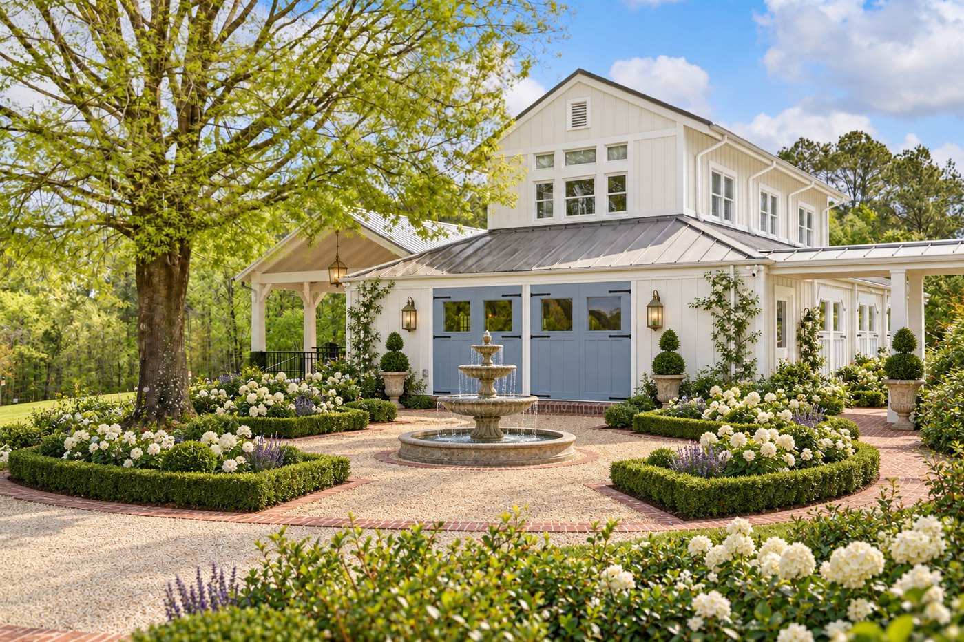 The pavilion — white board-and-batten with blue carriage doors behind the boxwood fountain garden