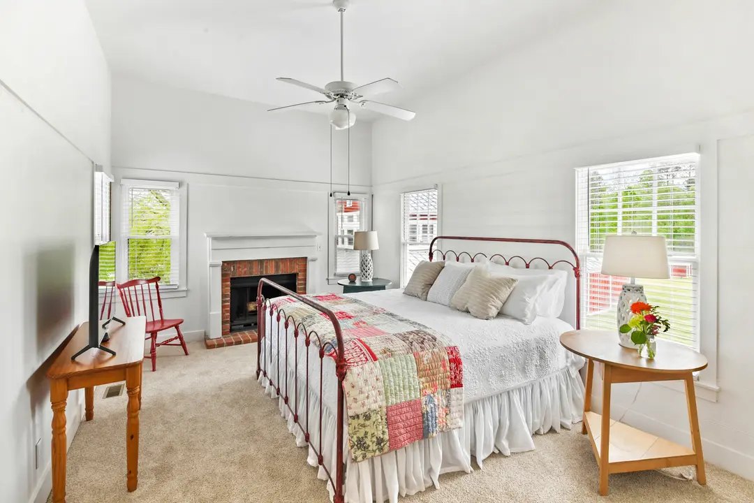An overnight room — iron bed, heirloom quilt, brick fireplace